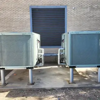 A pair of HVAC units installed on platforms to keep off the ground.